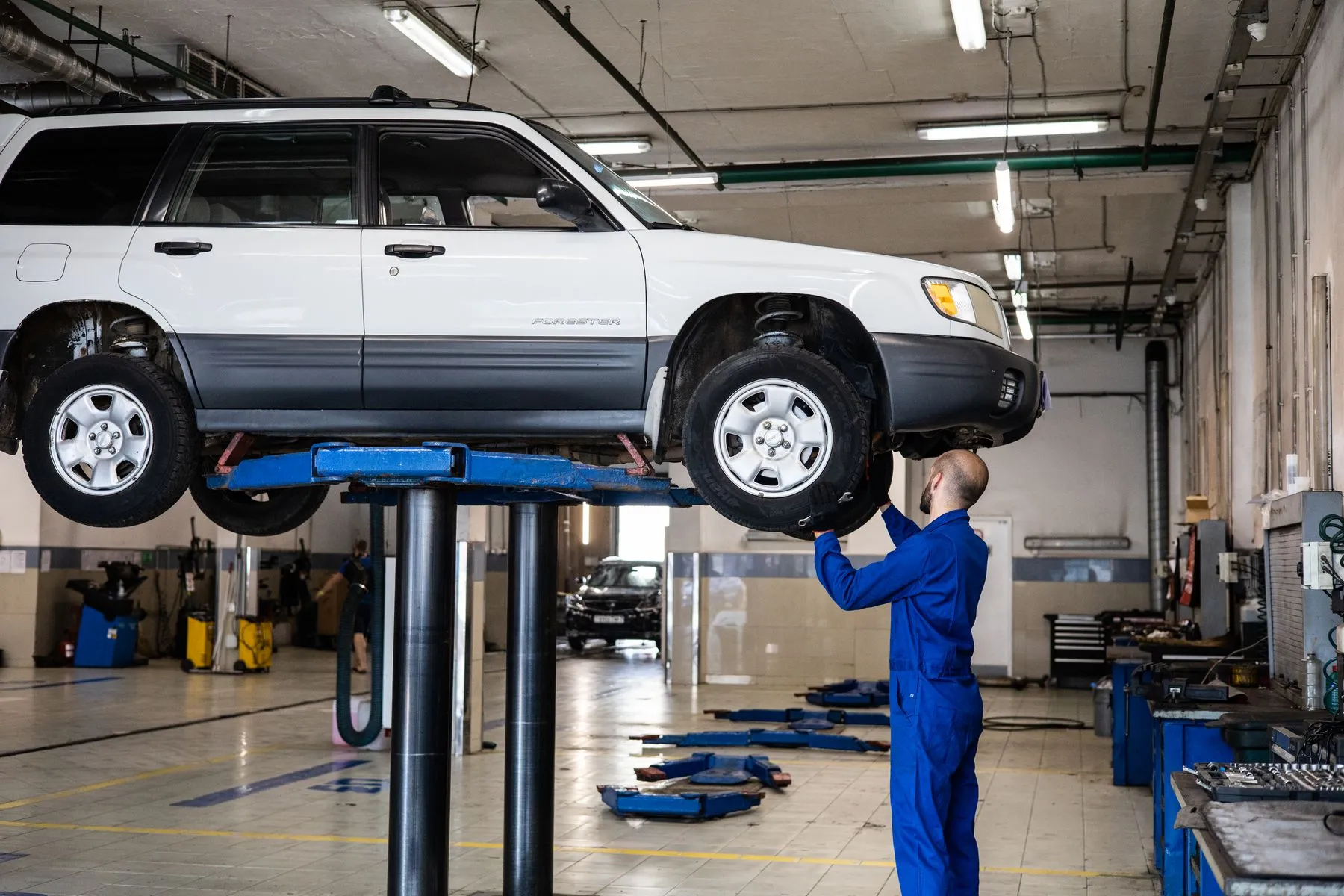 Bright vehicle service bay with a technician at work